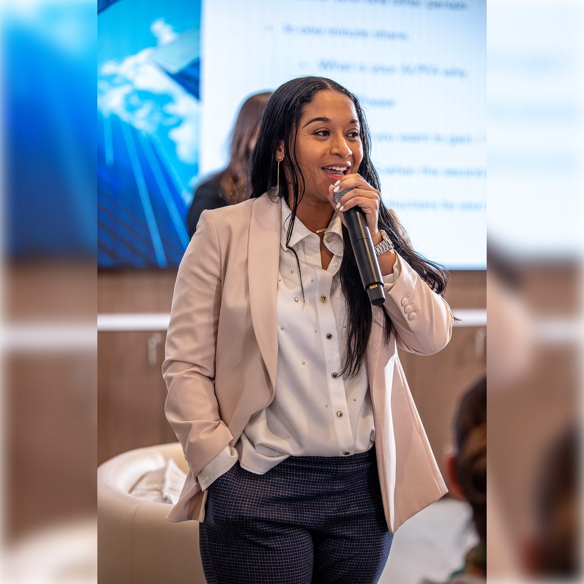 Woman speaking confidently with a microphone in a professional setting.
