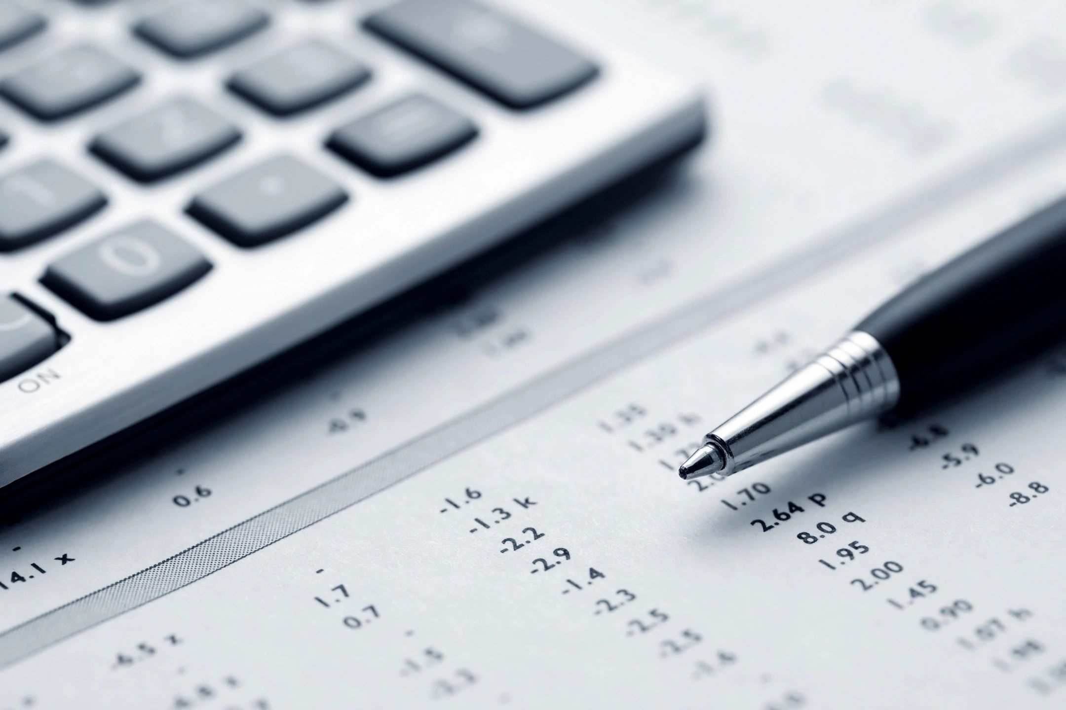 A pen resting on financial documents with a calculator nearby.